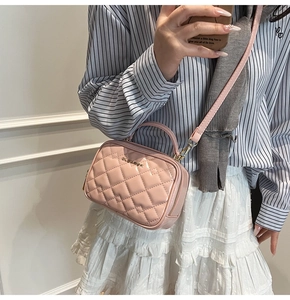 Vue détaillée du sac à bandoulière matelassé rose avec logo doré sur chemise à rayures