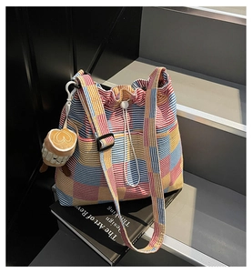 Detail of colorful plaid canvas bucket bag with drawstring closure and plush coffee cup charm