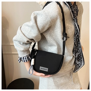 Detail of minimalist black nylon half-moon crossbody bag with woven decorative elements