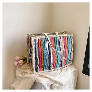 Detail of colorful striped woven tote bag with white leather handles on a minimal background