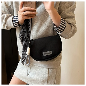 Detail of black crescent crossbody bag in nylon mesh with MERREY logo and woven charm