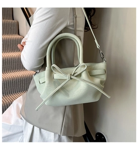 Détail du sac à main vert menthe en cuir grainé avec nœud et côtés plissés élégants