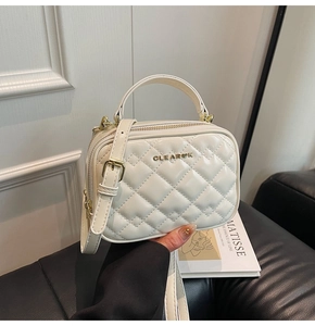 Gros plan sur un sac bandoulière blanc en similicuir matelassé avec logo doré