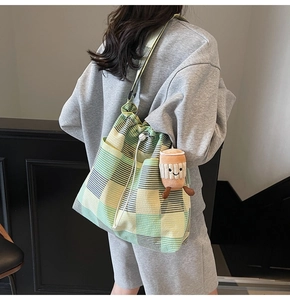 Detail of colorful plaid canvas bucket bag featuring a cute smiley coffee cup plush charm