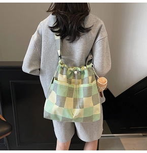 Detail view of green and yellow plaid canvas bucket bag with drawstring and cute charm