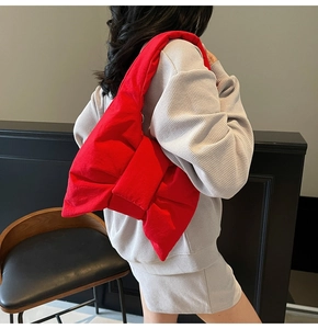 Detailed side view of a large red puffy bow shoulder bag with thick padded straps