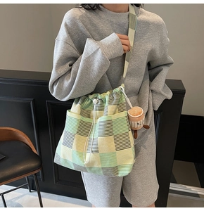 Detail of yellow and green plaid tote bag with drawstring closure and plush pendant