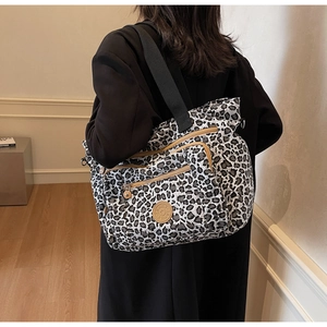 Detail of leopard print tote bag featuring multiple zip pockets and wide shoulder strap
