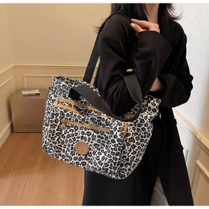 Detail of leopard print tote bag with multiple zipper compartments and brown leather accents
