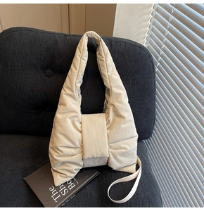 Macro shot of beige bow-shaped puffy shoulder bag texture on black velvet sofa