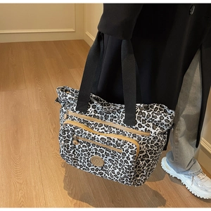 Detail shot of leopard print tote bag with multiple zip pockets and black woven straps