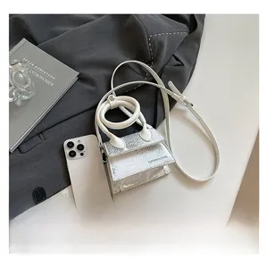 Mini-Handtasche in Silber mit Schlangenmuster im Größenvergleich zum Smartphone
