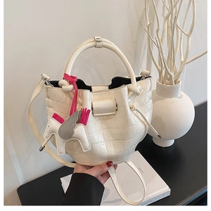 Macro detail of creamy white stone-patterned bucket bag with decorative pony charm accessory