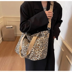 Detail showing the textured leopard print canvas and wide woven strap on a tote bag