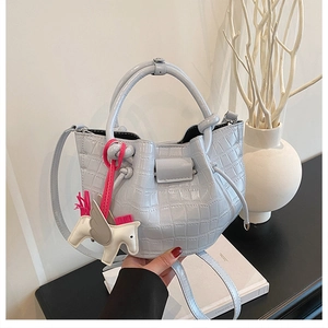 Detail of light blue croc-embossed bucket bag with a stylish pegasus bag charm