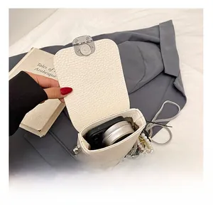 Detail of white lychee leather mini crossbody bag with pearl chain and silver clasp