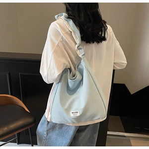 Detail of light blue tote bag featuring a stylish ruched shoulder strap and woven brand tag
