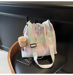 Detail of macaron plaid bucket bag with seersucker texture and coffee plush charm