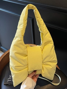 Modern bright yellow bow-shaped padded nylon underarm bag with puffy quilted texture