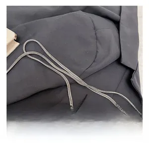 Close-up of high-quality silver metal chain strap on textured grey suit fabric backdrop