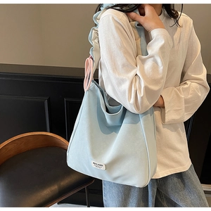 Light blue tote bag with ruffle strap and pink ring charm worn by a fashion model
