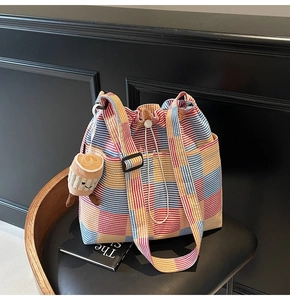 Detail of colorful striped bucket tote with drawstring closure and cute plush charm