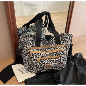 Macro shot of nylon leopard print tote bag featuring dual front zipper pockets and logo detail
