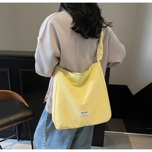 Detail of light yellow canvas tote bag showing the textured fabric and brand label