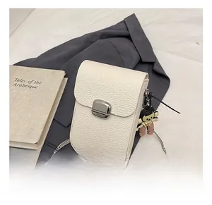Close-up of white pebble leather phone bag with silver metal clasp and fine chain strap