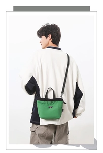Detail of green nylon mini crossbody bag with drawstring closure and black strap on model