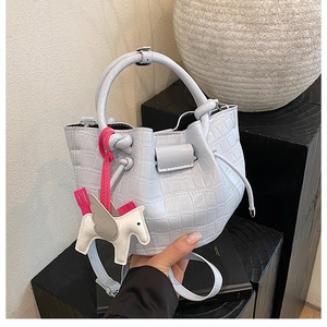 Close-up of stone texture leather bucket bag with a stylish pegasus bag charm and ring handle
