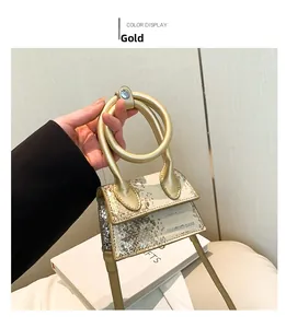 Nahaufnahme einer goldenen Mini-Umhängetasche aus Leder mit metallischer Schlangenprägung