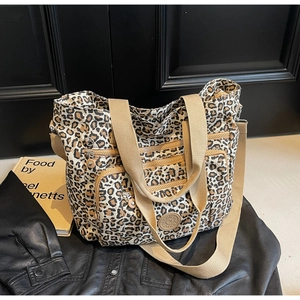 Detail view of leopard print canvas tote bag featuring triple zipper front pockets