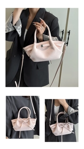 Détail du sac à main en cuir rose clair à texture litchi avec nœud délicat et bandoulière