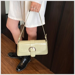 Detail of light green oil wax leather handbag with a large silver round metal buckle