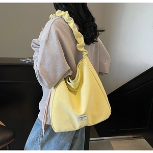 Detail of the yellow tote bag featuring a gathered ruched shoulder strap and woven fabric