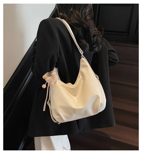Détail du sac hobo en similicuir beige avec plis souples et pendentif ours en peluche