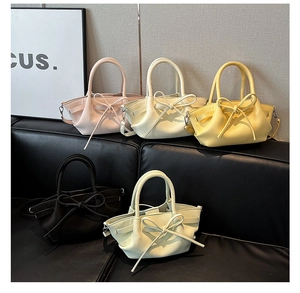 Détail de cinq sacs seaux aux couleurs macaron avec nœuds sur un canapé en cuir