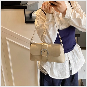Close-up of a beige oil wax leather shoulder bag with a silver circular buckle detail