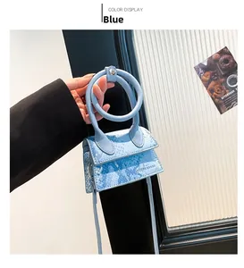 Detail der blauen Mini-Handtasche mit Schlangenmuster, Ringgriff und Schultergurt