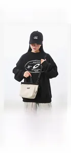 Unisex light beige sporty crossbody bag with black strap shown on model in streetwear style