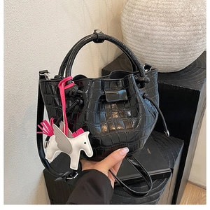 Detail of black faux leather bucket bag with stone pattern and white pony charm