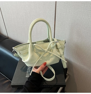 Détail du sac seau en cuir grainé vert clair avec une grande décoration de nœud