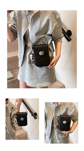 Detail of black lychee grain crossbody bag with silver buckle and doll pendant