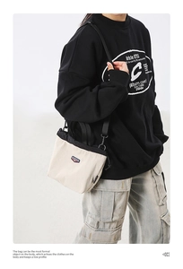 Detail view of cream canvas crossbody bag with black drawstring closure and strap