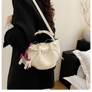 Detail of white crocodile pattern bucket bag with pink horse charm on model