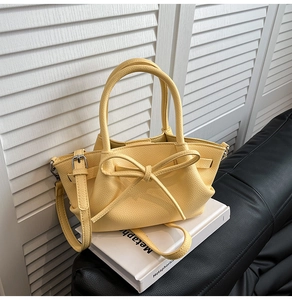 Détail du sac cabas jaune avec nœud en cuir grainé litchi et finitions métalliques