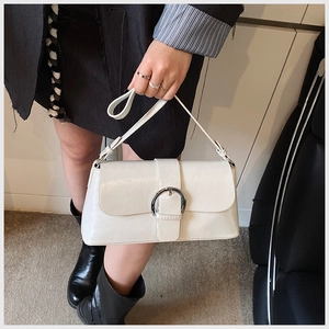 Detailed macro view of white leather shoulder bag with a large silver metal buckle