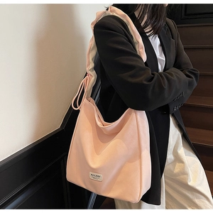 Detail of soft pink tote bag with ruffled shoulder strap and side drawstring on model
