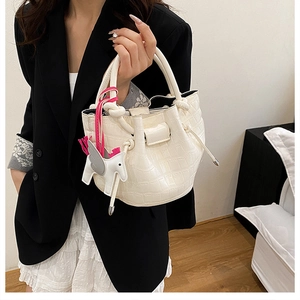 Detail of white crocodile pattern bucket bag with pegasus charm on fashion model